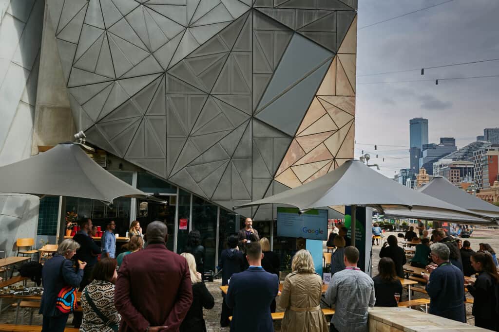 An crowd of people gathered in Melbourne's Federation Square, listening to a speaker at Jobsbank's first Meet The Suppliers event.