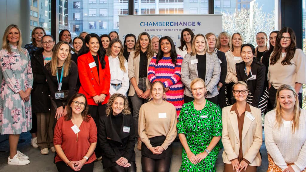 A group of women all smile and sit for the camera at an event. They are all in bright clothes.