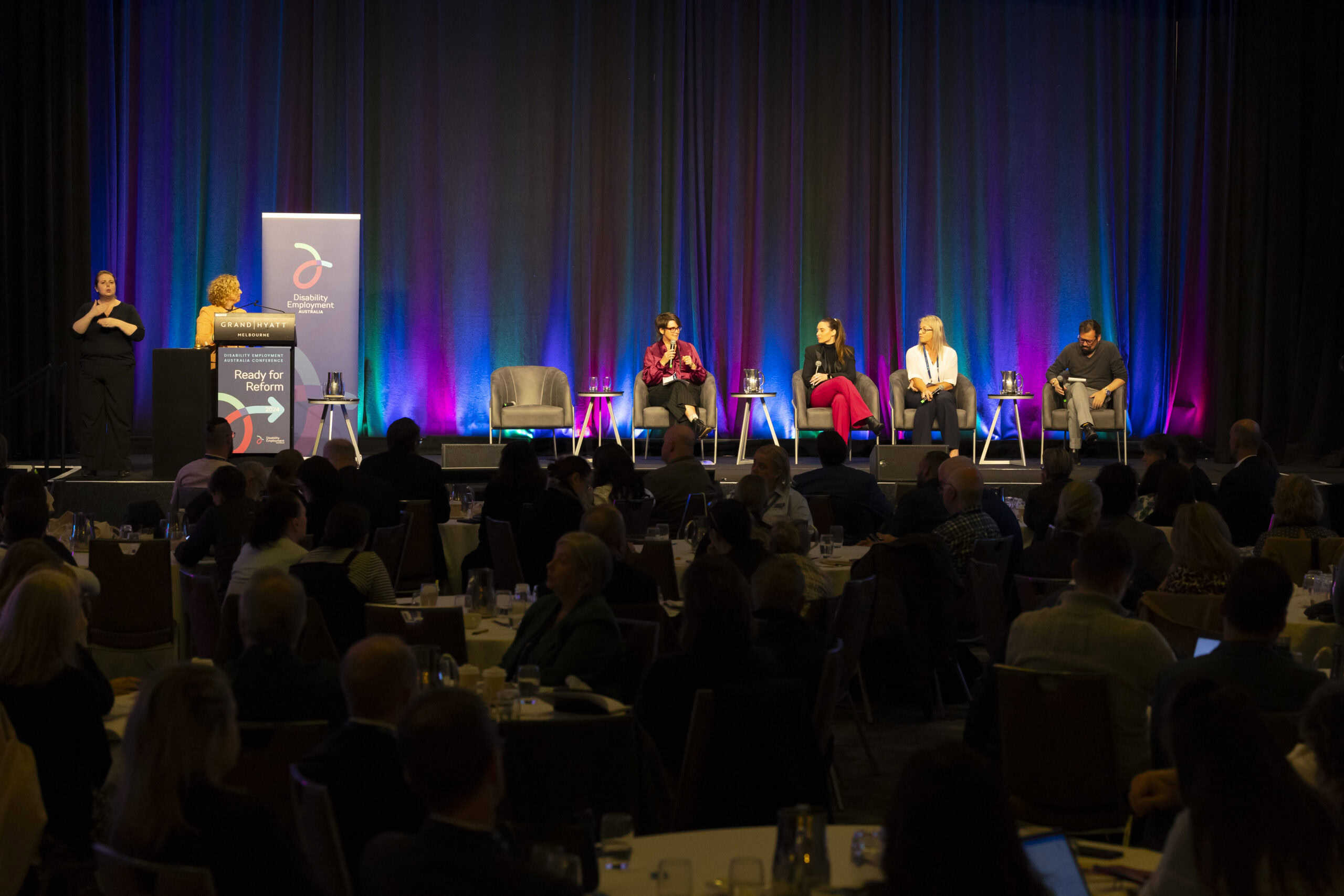 A panel presentation at a conference, with four people on the panel and a moderator behind a lectern. The image is from the DEA Conference 2024. It is a wide angle shot so we can't see the people in detail.
