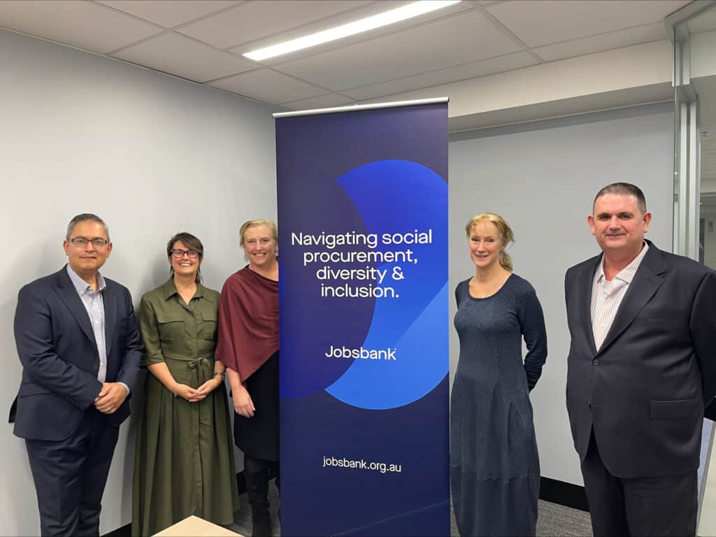 Five people, all dressed in professional clothes, stand in front of a Jobsbank banner. There are three women and two men.
