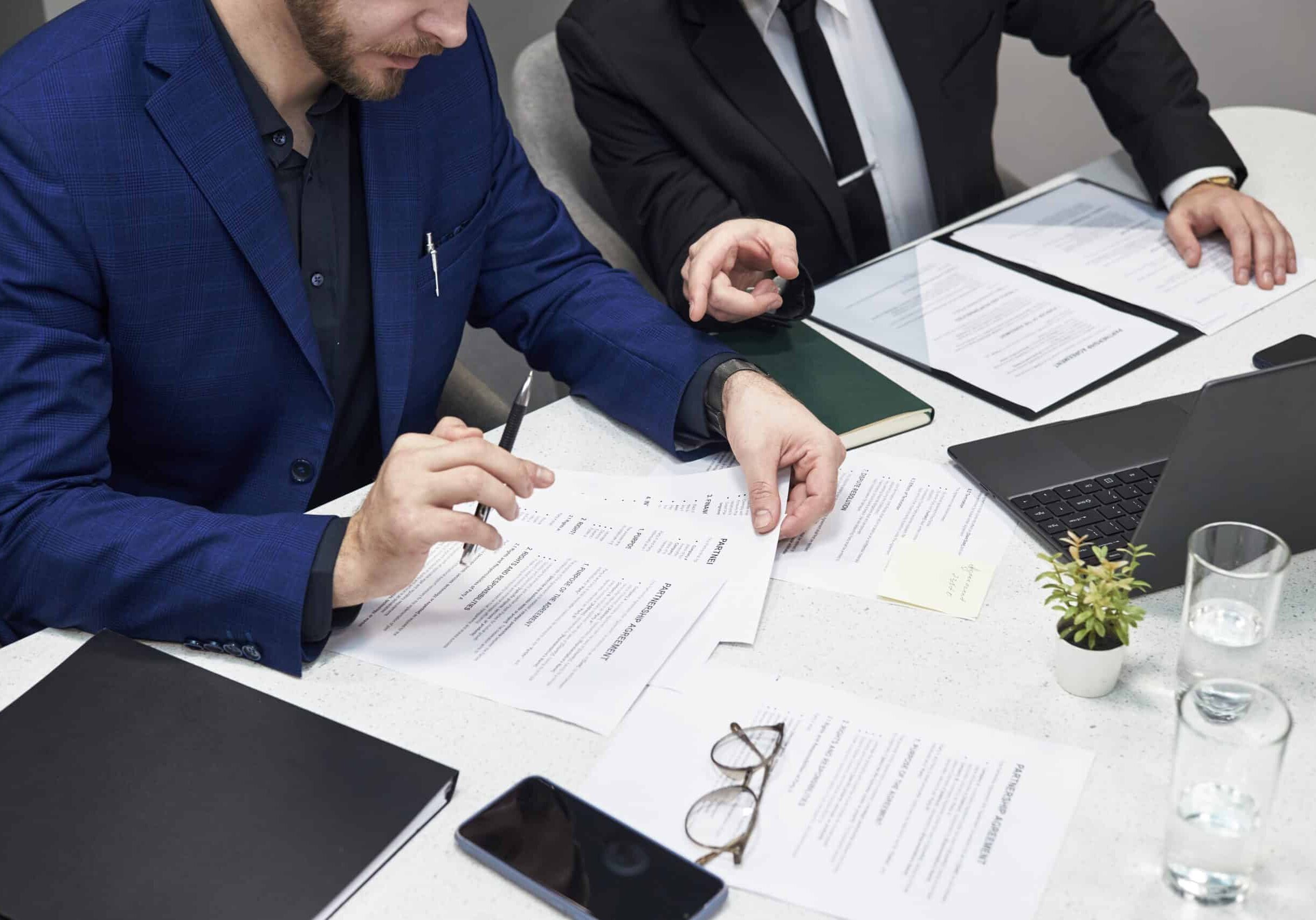 Two,Male,Managers,In,Formal,Suits,Discussing,Documents,At,Desk,